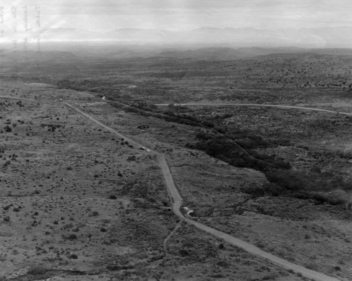 (Figure 2) View of project area from top of Round Mountain, looking west. LA 10832 is located at the bend in Old Mescalero Road in the left center of photo; vehicles are parked at the site.